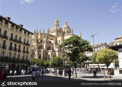 Tourists and locals alike enjoying life in Plaza Mayor and the Gothic Cathedral of Segovia, Spain