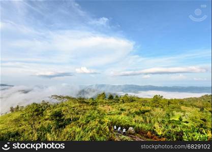 Tourists are walking on nature trails amidst the beautiful landscape of mountain range sky cloud and fog in the winter at Phu Chi Fa Forest Park, Chiang Rai Province, Thailand