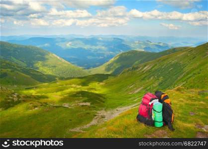 Tourists backpacks on top of high mountains