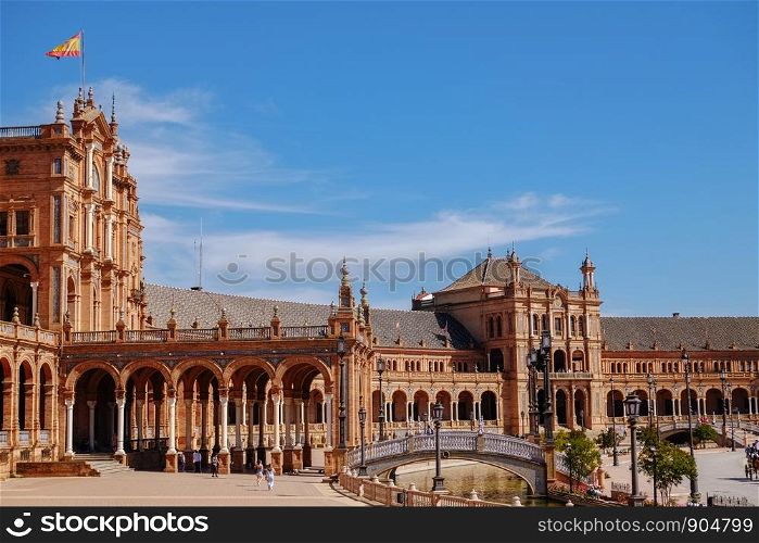 Tourists enjoy sightseeing around famous ancient landmark Plaza de Espana. Seville, Spain.