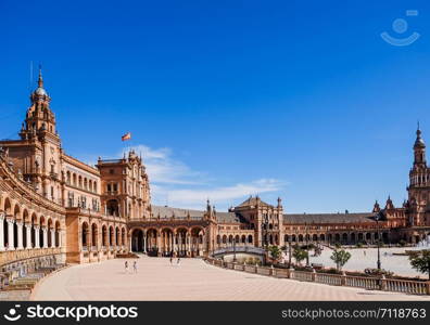 Tourists enjoy sightseeing around semi-circular building at the Plaza de Espana. Seville, Spain.