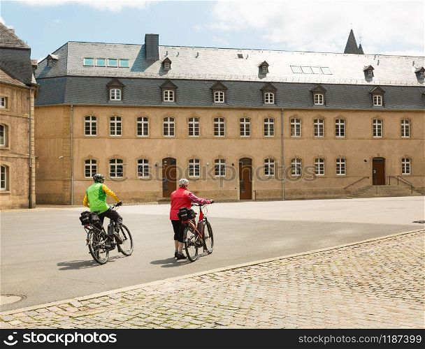 Tourists on bicycles, old European city street, panorama. Traditional architecture. Summer tourism and travels, famous europe landmark, popular places for vacation tour or holidays