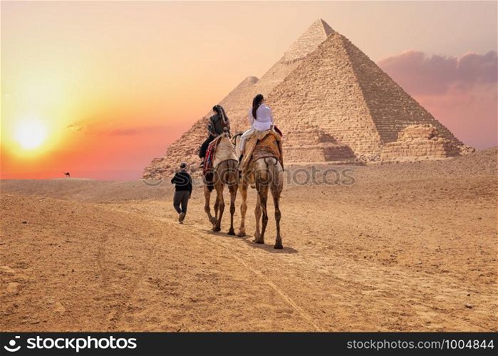 Tourists on camels near the Great Pyramids of Giza, Egypt.. Tourists on camels near the Great Pyramids of Giza, Egypt