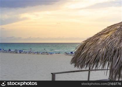 Tourists relax on Varadero sandy beach at sunset. Cuba.