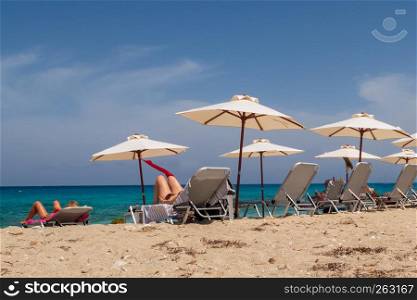 Tourists relaxing on sun loungers on the beach on Lefkada island, Greece