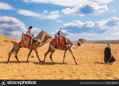 Tourists riding camels near the Pyramids of Giza.. Tourists riding camels near the Pyramids of Giza