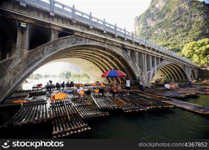 Tourists sitting on bamboo rafts under an arch bridge, Guilin Hills, XingPing, Yangshuo, Guangxi Province, China