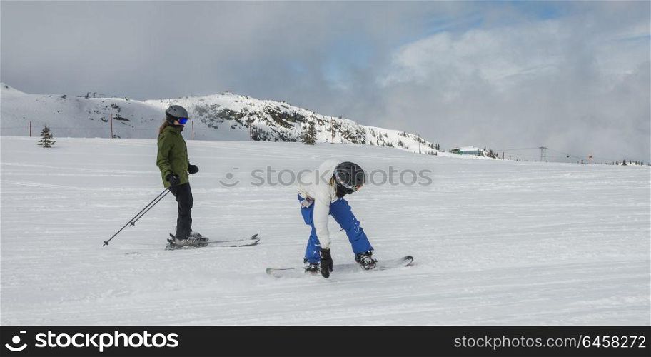 Tourists skiing and snowboarding on snowy mountain, Whistler, British Columbia, Canada