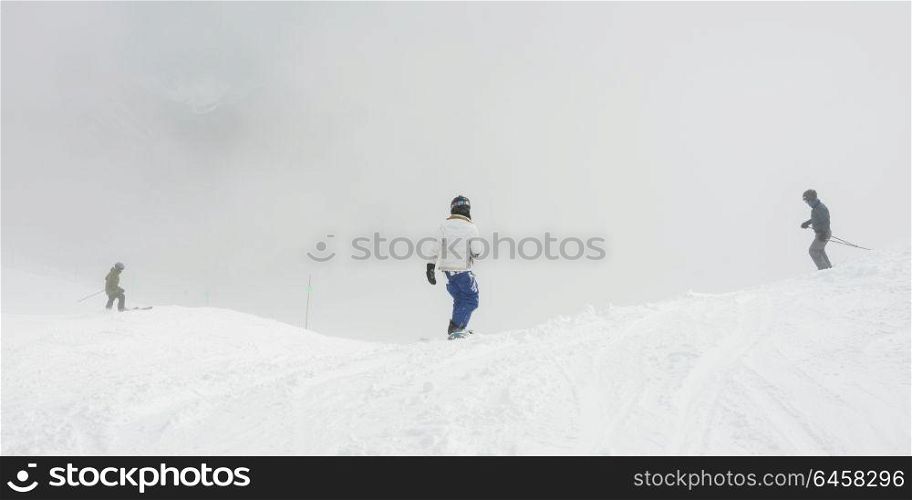 Tourists skiing and snowboarding on snowy mountain, Whistler, British Columbia, Canada