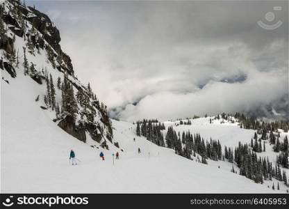 Tourists snowboarding and skiing on snow covered mountain, Whistler, British Columbia, Canada
