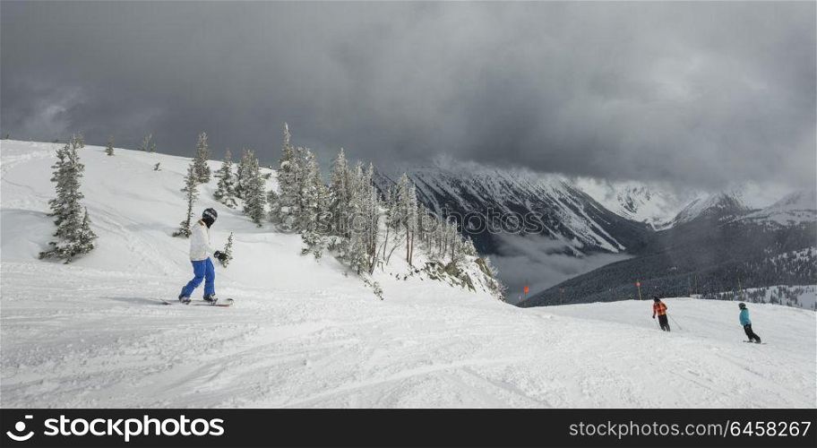 Tourists snowboarding and skiing on snowy mountain, Whistler, British Columbia, Canada