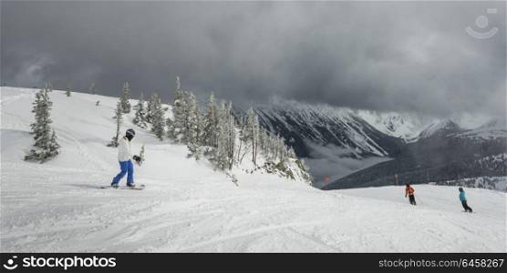 Tourists snowboarding and skiing on snowy mountain, Whistler, British Columbia, Canada