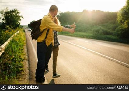 tourists stop cars on the road. young people traveling hitchhiking. summer road.. tourists stop cars on the road. young people traveling hitchhiking. summer road