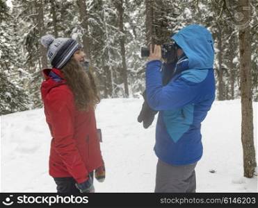 Tourists taking a picture in snow covered forest, Johnston Canyon, Banff National Park, Alberta, Canada