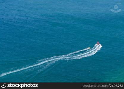 Tourists taking ride by speed boat on rubber tube boat on waves in ocean, aerial view