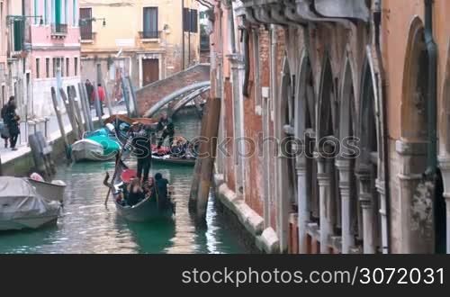 Tourists traveling by gondolas on the canal. Traditional way of sightseeing of the city with its vintage architecture and elegant decay