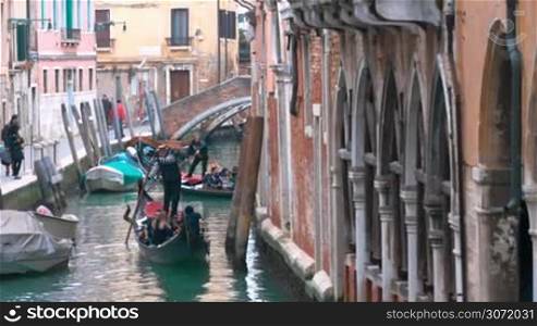 Tourists traveling by gondolas on the canal. Traditional way of sightseeing of the city with its vintage architecture and elegant decay