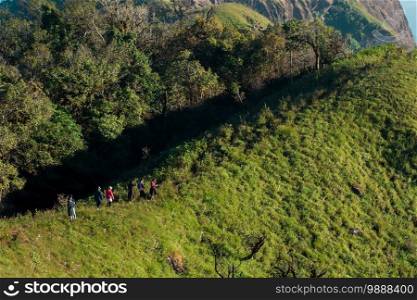 Tourists walk on a high hill to see the scenery on the mountain.