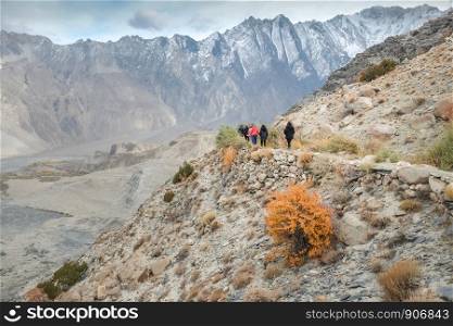 Tourists walking along the hiking path amid Karakoram mountain range in Passu, Gojal Hunza. Gilgit Baltistan, Pakistan.