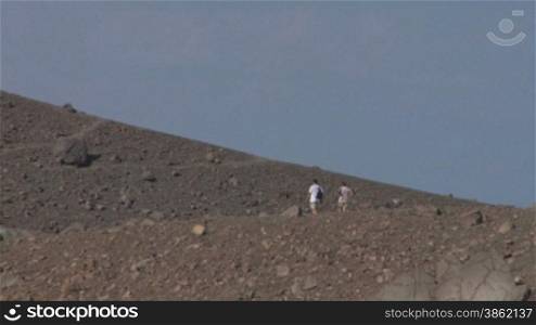 Tourists walking on an edge of volcano crater