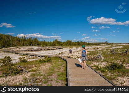 Tourists with backpack hiking in Yellowstone National Park near Firehole River, Wyoming, USA