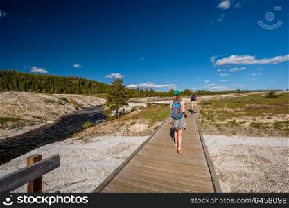 Tourists with backpack hiking in Yellowstone National Park near Firehole River, Wyoming, USA