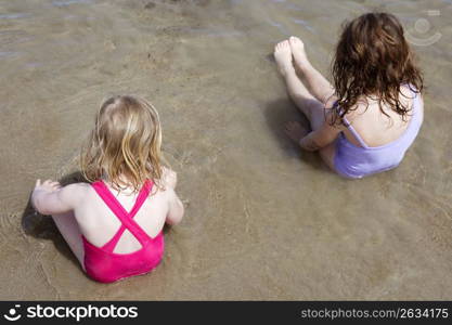 tow sisters sit on beach bathing suit swimsuit back view summer vacation