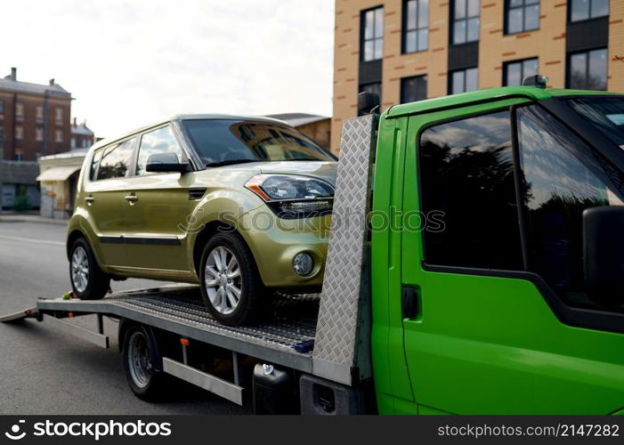 Tow track vehicle taking away broken faulty car down street. Automotive emergency service concept. Tow track vehicle taking away broken car