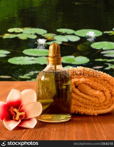 Towel, bottleRolled towel, bottle with oil and orchid flower on wooden background with oil and orchid flower.. Towel, bottle with oil and orchid flower.