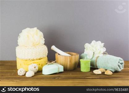 towel spa stones loofah sponge soap candle flower mortar pestle wooden surface