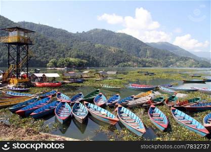 Tower and wooden boats on the Phewa lake in Nepal
