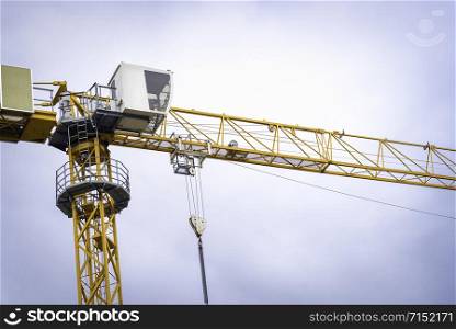 Tower crane at a construction site in the german city Stuttgart. Yellow tower crane close-up low-angle view against the blue sky
