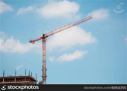 Tower crane in construction site over blue sky with clouds .