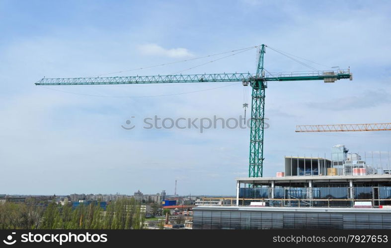 Tower crane near a building under construction over clody sky