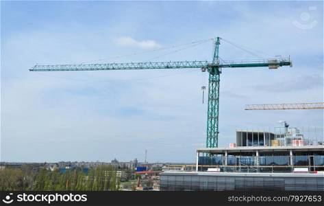 Tower crane near a building under construction over clody sky