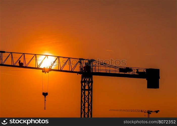 Tower crane on a construction site at sunset or sunrise