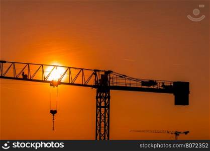 Tower crane on a construction site at sunset or sunrise