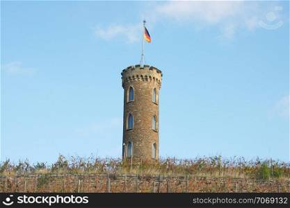 Tower in the vineyard with the German flag and a blue sky in the background