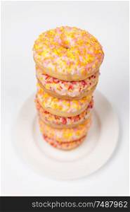 Tower of donuts or doughnuts with colorful frosting or icing and sprinkles on a white plate
