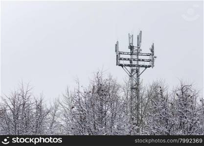 Tower with antennas. Antenna among the trees in winter. Antenna in the snow.