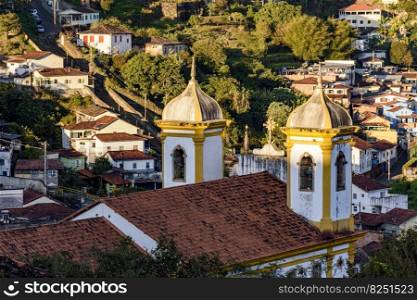Towers and bells of an old baroque church with the houses of Ouro Preto city in the background. Towers and bells of an old baroque church in Ouro Preto