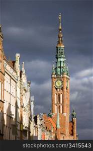 Town Hall (Polish: Ratusz Glownego Miasta) clock tower in the Old Town of Gdansk (Danzig) in Poland, bathed in sunlight, just before the storm