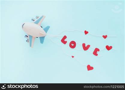 Toy airplane and the bright red word LOVE on the ropes behind. blue background.