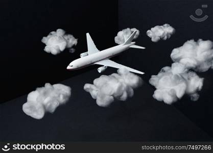 Toy airplane fly with fake white clouds on mockup three dimensional black background ,travel concept