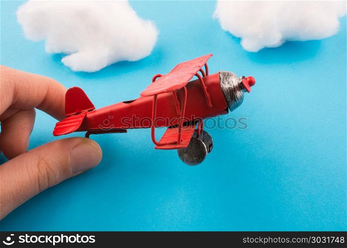 Toy airplane in hand and clouds. Retro styled red model airplane in hand, blue sky and clouds