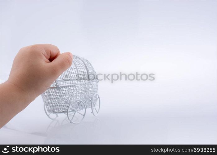 Toy baby carriage in hand made of metal on white background