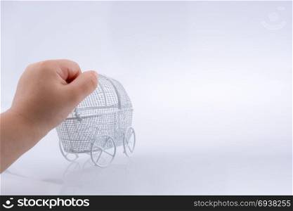 Toy baby carriage in hand made of metal on white background