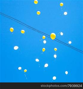 toy balloons float in blue sky in city