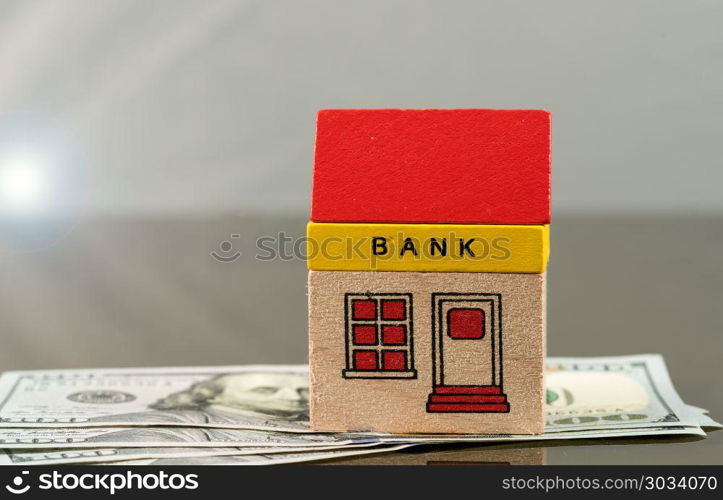 Toy bank building on US dollar assets. Toy brick bank building sitting on US 100 dollar bills as illustration of too big to fail banks. Repeal of Dodd-Frank could jeopardize the assets of large investment banks. Toy bank building on US dollar assets