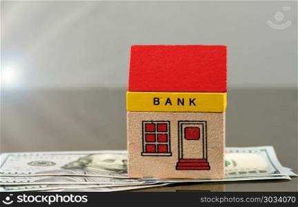 Toy bank building on US dollar assets. Toy brick bank building sitting on US 100 dollar bills as illustration of too big to fail banks. Repeal of Dodd-Frank could jeopardize the assets of large investment banks. Toy bank building on US dollar assets